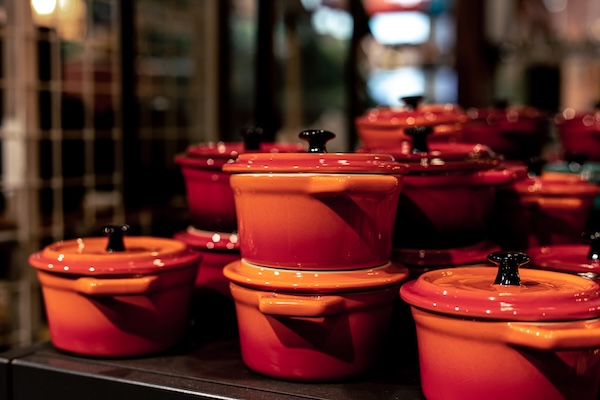 Small Dutch ovens in a shop window, miniature crockery on a blurry background.